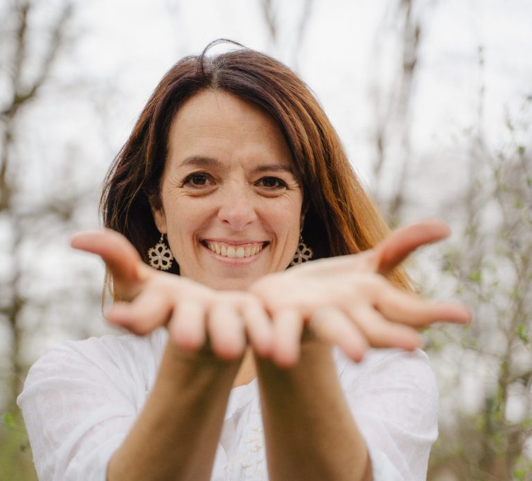 Frau mit lächelndem Gesicht, die ihre Hände offen und einladend ausstreckt.